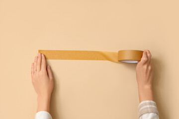 Female hands with adhesive tape on beige background