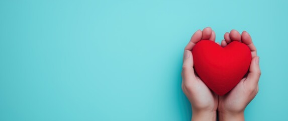 Hands holding a vibrant red heart on a turquoise background, symbolizing love, care, health, and charitable giving with copy space
