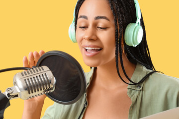 Female African-American radio presenter with microphone on yellow background, closeup