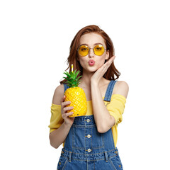 Young woman with yellow sunglasses holding a pineapple drink