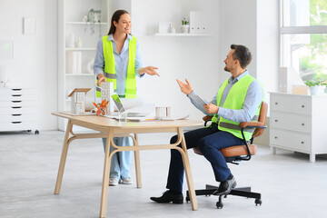 Young architects working with 3D house model at table in office