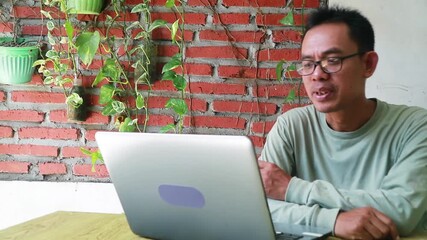 Asian man actively communicating through a webcam, perfectly suited for remote work software promotions, international business networking, and digital family connectivity advertisements