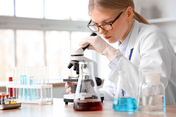 Female scientist looking through microscope in laboratory