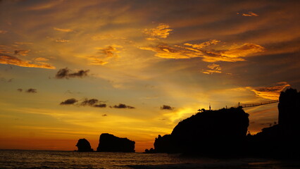 Sunset over silhouette rocky coastline landscape.