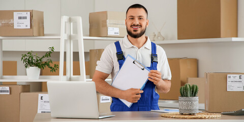 Male worker with clipboard at table in warehouse
