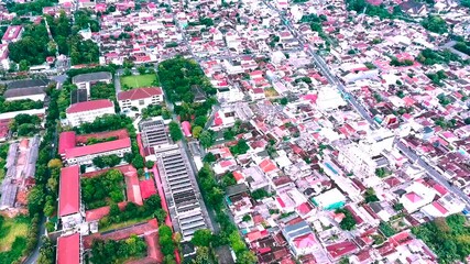 Drone view of a bustling city with red-roofed buildings and trees - Powered by Adobe