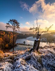 Scenic vista of a tranquil lake nestled among colorful autumn trees under a partly cloudy sky at sunrise