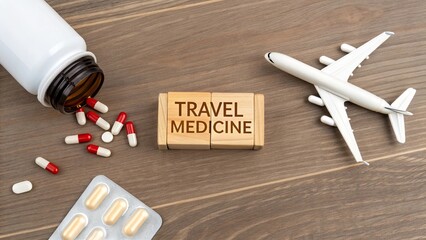 Wooden cubes labeled 'Travel Medicine' with a single airplane figurine, pills spilled from bottle wooden desk. Healthcare vaccination preparation, international travel safety planning