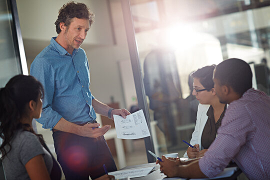 Documents, meeting and presentation with business people in office together for design or planning. Paperwork, pitch and proposal with designer man speaking to colleagues in boardroom for review