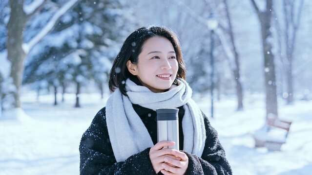 冬の公園で水筒を持ち微笑む日本人女性
