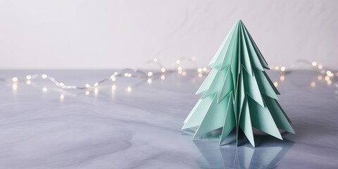 Origami paper christmas tree with blurred fairy lights on marble