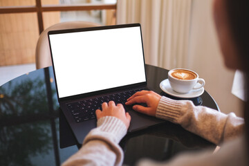 Mockup image of a woman working and typing on laptop computer with blank white desktop screen in cafe