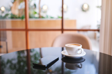 A mobile phone and a coffee cup on the table in cafe