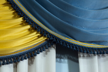 Close-up of blue and yellow fabric draped with dark blue tassel fringe