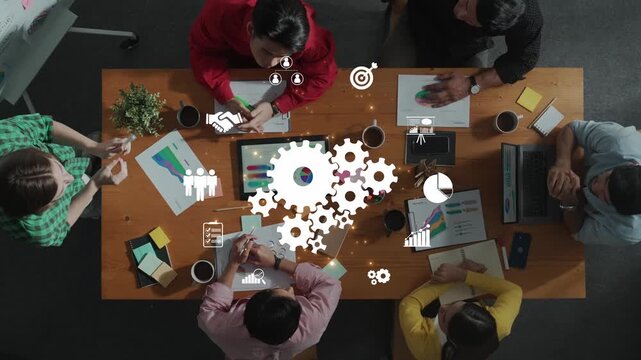 Aerial view of a diverse team engaged in a collaborative meeting in a modern workspace, utilizing data visualization and creative strategy planning tools for effective brainstorming. Raster