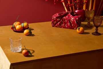 A festive scene featuring tangerines, gift packaging, and glassware. The red and gold palette supports premium product displays. Lunar New Year, Chinese new year concept