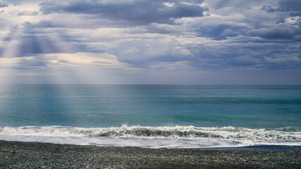 Beach scene with waves under cloudy sky over coastal seashore horizon