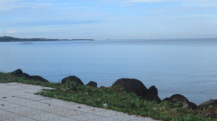 Rocks are arranged on the edge of the beach, the sea water is calm
