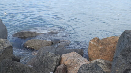 Rocks are arranged on the edge of the beach, the sea water is calm