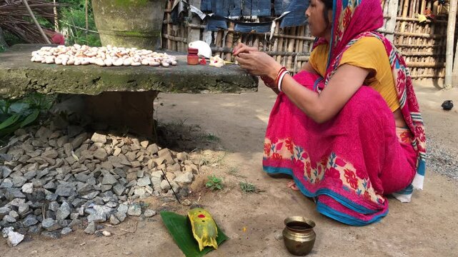 Odia Woman Performing Basumati Snana Mother Earth Ritual During Raja Festival in Odisha, India. The ritual honors Mother Earth (Basumati) by decorating a grinding stone (Shilpua) with flowers