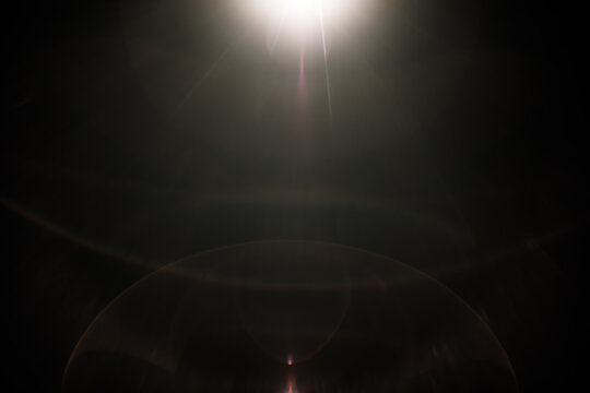 Real optical lens flare with cinematic ghosting arc and light leaks on black background for overlay