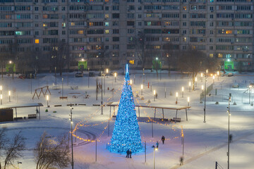 a Christmas tree in the park, white snow falling, people making snowmen and walking in the park in Orenburg