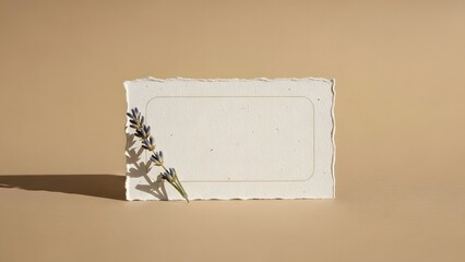 A blank white rectangular card with rough edges and a decorative metal figure leaning against it on a beige background
