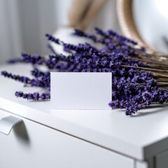 A blank card rests before a lavender bouquet on a white dresser. A mirror is reflected