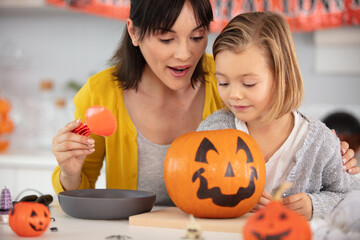 a mother and her daughter carving pumpkin