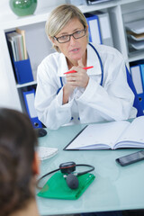 bearded senior man talking with redhead female doctor in clinic