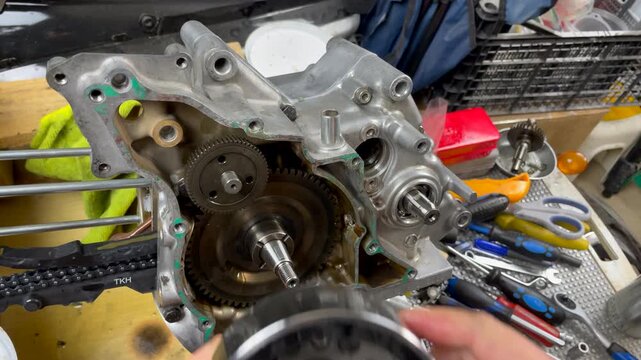Close-up overhead POV shot of mechanic carefully installing flywheel onto crankshaft, aligning the notch for the safety pin, demonstrating precise assembly on a home garage workbench