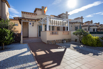 Sunny Mediterranean townhouse exterior with front patio and pergola
