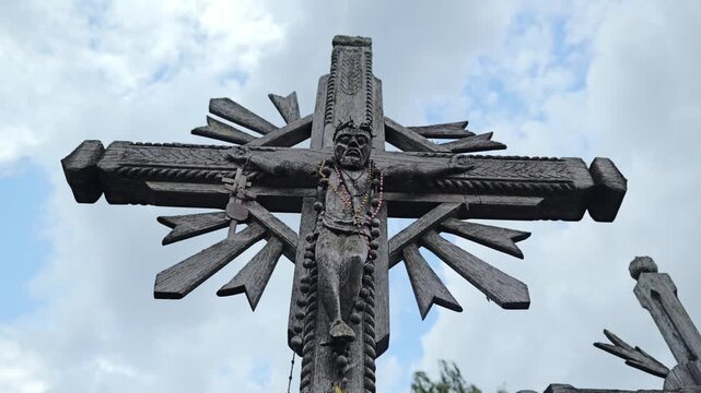 Wooden crucifix sculpture standing outdoors, in day at pilgrimage site Lithuania