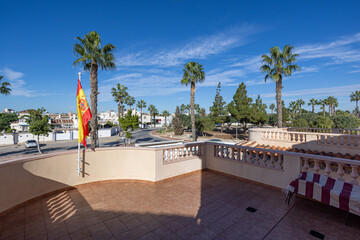 Sunny rooftop terrace with Spanish flag and palm trees