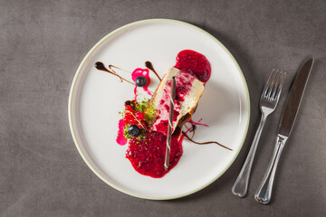 Cheesecake slice topped with fresh berries and vibrant sauce