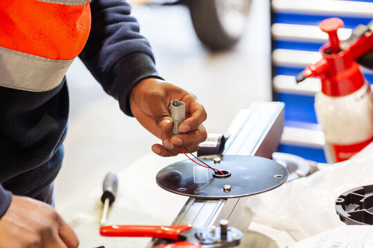 Male technician working on the wiring on circular metal plate for light bar