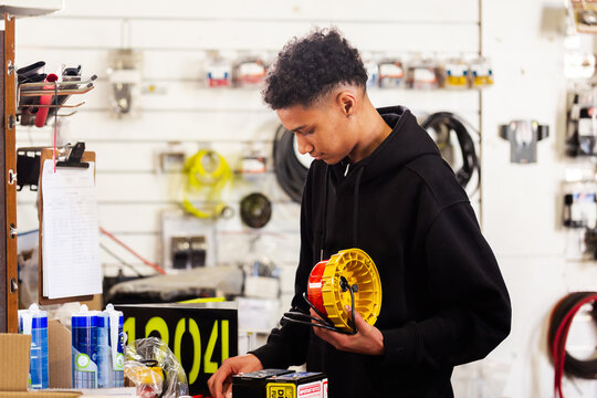 Young male mechanic holding a mining vehicle light inside workshop testing parts before installation