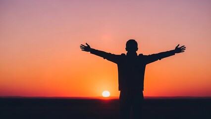 Silhouette of a young man with arms outstretched against a vibrant sunset backdrop