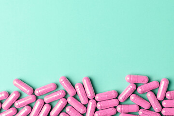 Pink supplement capsules form bottom border on mint background, calm medical banner with generous copy space for promo text.