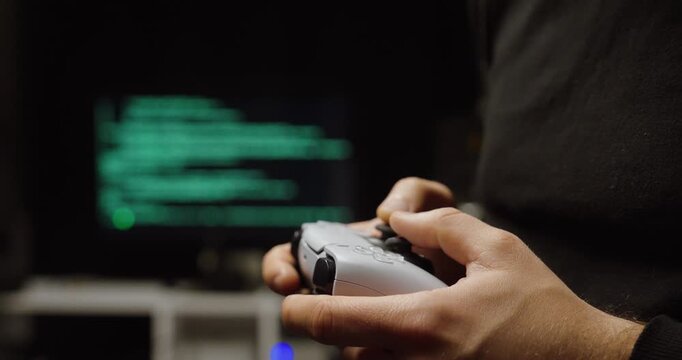 Cinematic shallow-focus shot of hands holding a game controller while a monitor displays glowing code&mdash;concept for AI gaming, game development, automation, and digital entertainment technology.