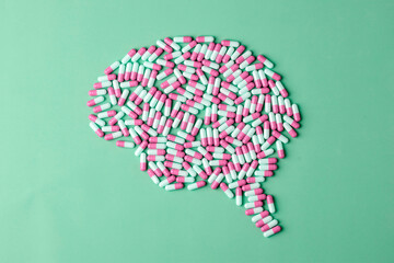 Pink and white capsules shape brain silhouette on green background, focused concept for mental health, cognition, nootropic care.