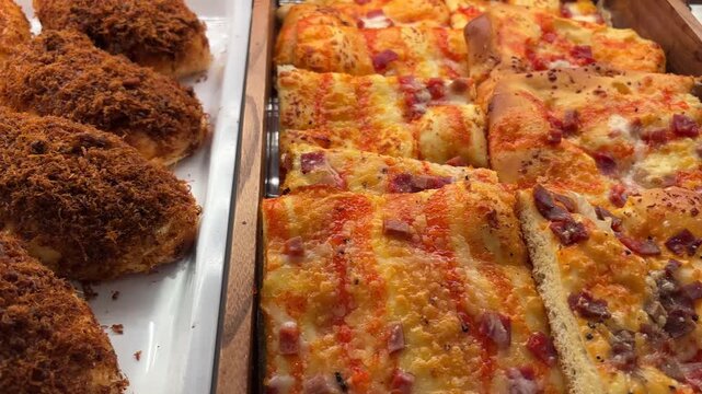 Panning shot of meat floss buns and pizza slices in a bakery shop