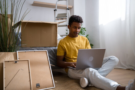 Man sitting on floor at home using laptop during moving