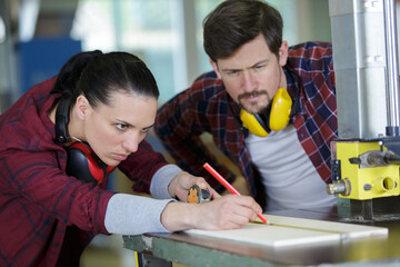 female carpenter marking wood in workshop