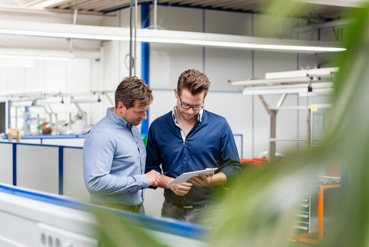 Business meeting with tablet in production hall of modern industry