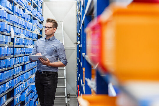 Businessman checking inventory in warehouse production hall