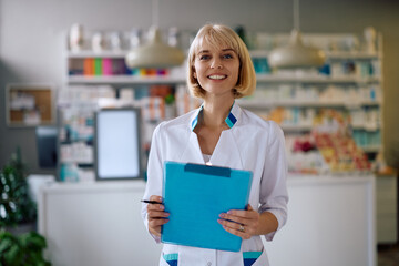 Portrait of happy female pharmacist in drugstore looking at camera.