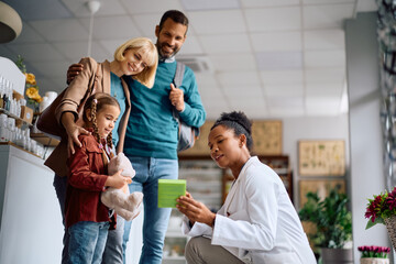 African American pharmacist advising family in choosing vitamins in drugstore.
