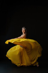 Woman dances with a snake in a vibrant dress during a cultural performance at night