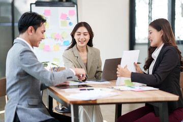 Group of Asian businesspeople sits down for a business investment planning meeting.
